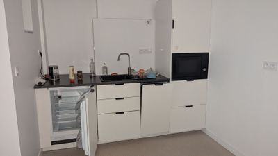 une petite cuisine avec des placards blancs et des plans de travail noirs