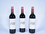 trois bouteilles de vin rouge posées sur une table blanche