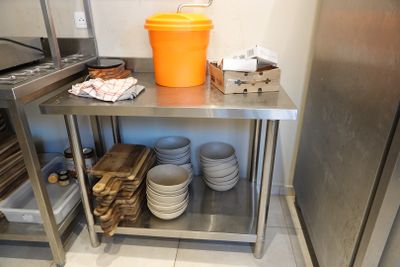 many plates and bowls on a stainless steel shelf in the kitchen