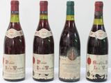 four bottles of wine are lined up on a white surface
