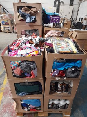 Plusieurs cartons de vêtements sont empilés les uns sur les autres dans un entrepôt