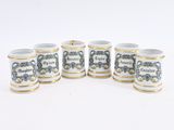 six small white and blue mugs with gold rims on a white surface