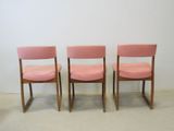 three pink chairs sitting next to each other in a room