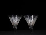 two empty wine glasses sitting on a table with a black background
