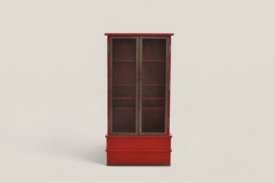 une armoire rouge avec une porte vitrée au milieu