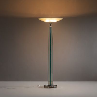 un lampadaire en verre surmonté d'un abat-jour blanc