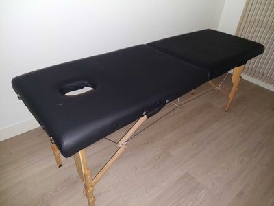 black massage table with a hole in the middle of it