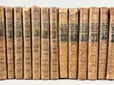 six vieux livres sont alignés sur une surface blanche