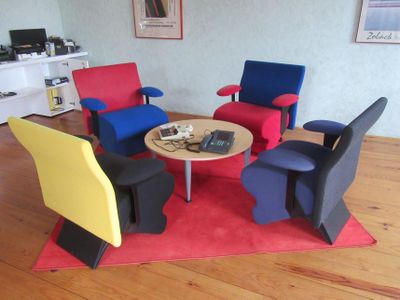 brightly colored chairs and a table in a living room with wood flooring