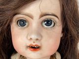 a close up of a doll ' s face with big blue eyes