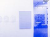 blue and white photograph of an empty room with paintings on the wall