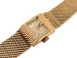 a close up of a wrist watch with a gold mesh band
