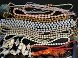 many different types of necklaces and bracelets laid out on a table