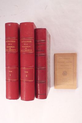 trois livres rouges posés sur une table blanche, à côté d'un livre