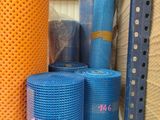 Plusieurs rouleaux de filet bleu et orange sont empilés sur une palette