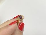 woman ' s hand holding a gold ring with a ruby stone