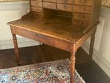 an old wooden desk with drawers and a rug on a wooden floor