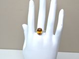 a hand with a ring on it that has a yellow stone on it