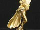 statue en or représentant une femme ailée, posée sur un socle noir