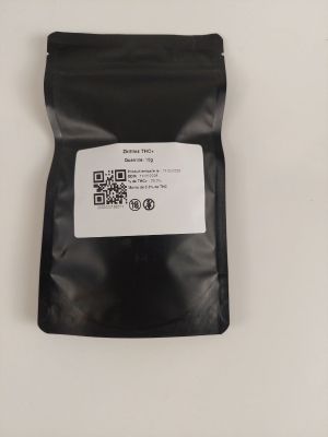 un gros plan sur un sac noir contenant de la nourriture posé sur une surface blanche