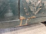 a dirty green car with a rusted door on the side of the road
