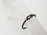 black leather bracelet with a gold clasp on a mannequin hand