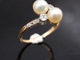 gros plan d'une bague en perles et diamants sur une surface noire