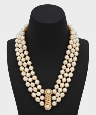 un collier de perles à trois rangs muni d'un fermoir en or, posé sur un mannequin
