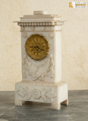 a white marble clock with a gold face on a table
