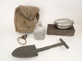 une pelle, une bouteille et un sac posés sur une table