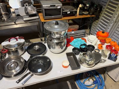 de nombreuses casseroles et poêles posées sur une table dans la cuisine