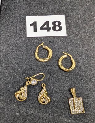 Trois paires de boucles d'oreilles et un collier sont exposés sur une table