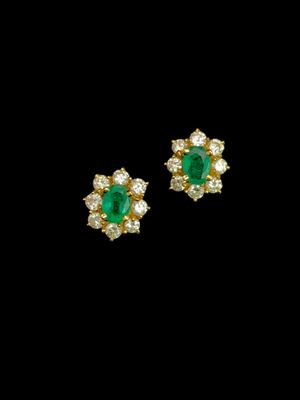 une paire de boucles d'oreilles en émeraude et diamant sur fond noir