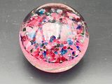 a glass ball with a pink base and colorful sprinkles on it