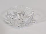 a clear glass bowl with a handle on a white surface