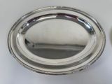 a silver plate on the table next to a spoon