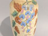 un vase jaune orné de fleurs et de feuilles bleues