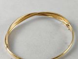 a close up of a gold bang bracelet on a white surface