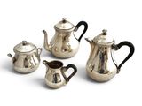 four pieces of silver tea and coffee set on a white surface