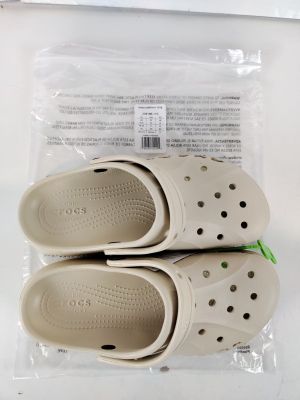 deux paires de Crocs se trouvent dans un sac en plastique posé sur une table