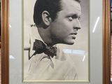 une vieille photo d'un homme portant un nœud papillon, dans un cadre doré