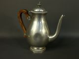 an antique silver teapot with a wooden handle on a black background