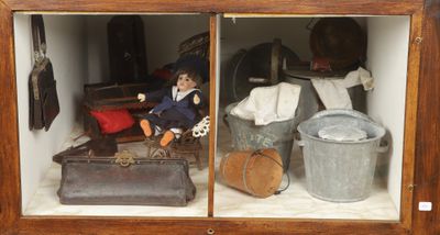 une poupée posée à l'intérieur d'une vitrine remplie d'objets