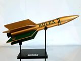 une maquette de fusée dorée et verte posée sur un socle noir