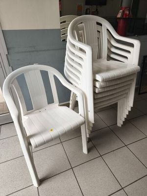 une pile de chaises en plastique blanc posées sur un sol carrelé