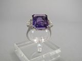 une bague en améthorate et diamant exposée sur un socle en acrylique transparent