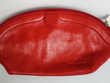 une image représentant un sac à main rouge posé sur une surface blanche