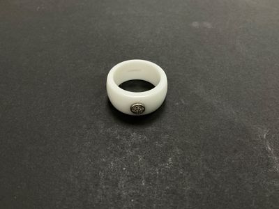 un anneau blanc posé sur une table, sur fond noir