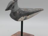 l'image d'un oiseau posé sur un socle en bois, sur fond blanc