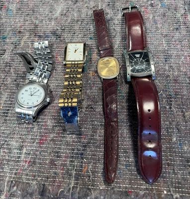 trois montres et une montre-bracelet sont posées sur une table